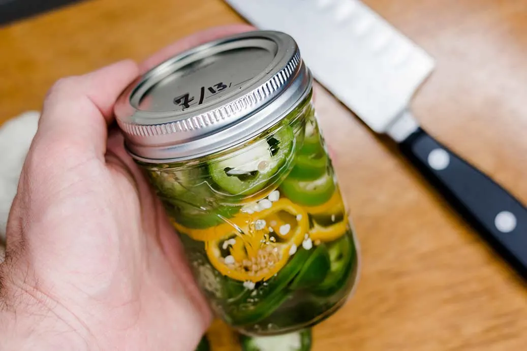 Hand holding jar of pickled jalapenos