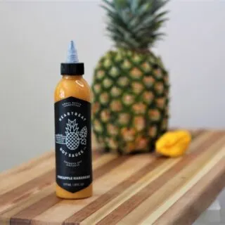 Heartbeat Pineapple Habanero Hot Sauce bottle with pineapple in the back