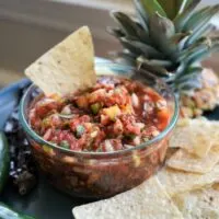 Pineapple jalapeno salsa in bowl with tortilla chip in salsa