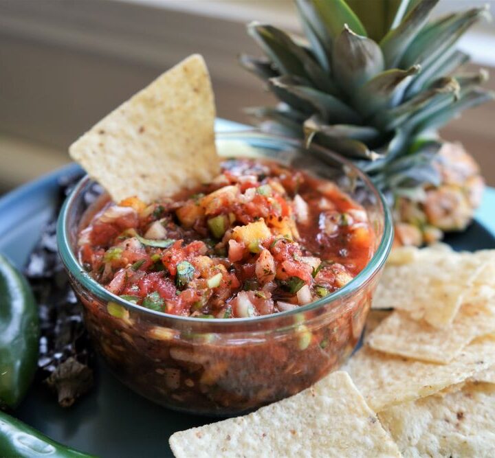 Pineapple jalapeno salsa in bowl with tortilla chip in salsa