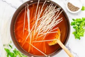 Adding rice noodles to Thai soup