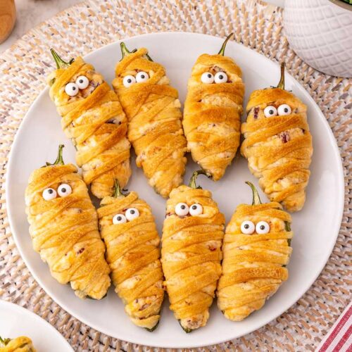overhead shot of plate full of wrapped jalapeno poppers made to look like mummies