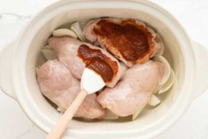 Chicken being coated in sauce