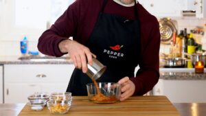 Pouring dried chili flakes into a heat-safe bowl
